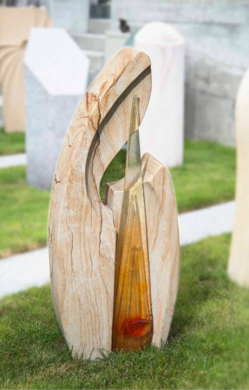 Abstrakte Steinskulptur mit einer Glasflasche im Inneren, auf grünem Gras.