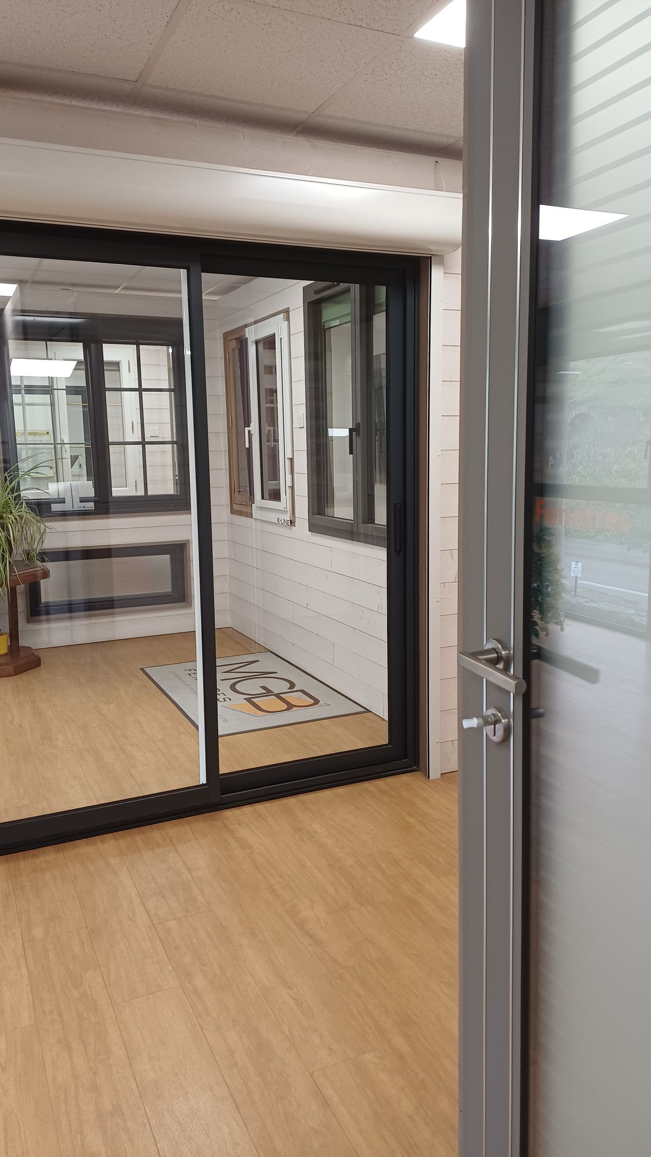 Porte-fenêtre noire en aluminium devant laquelle se referme un volet roulant