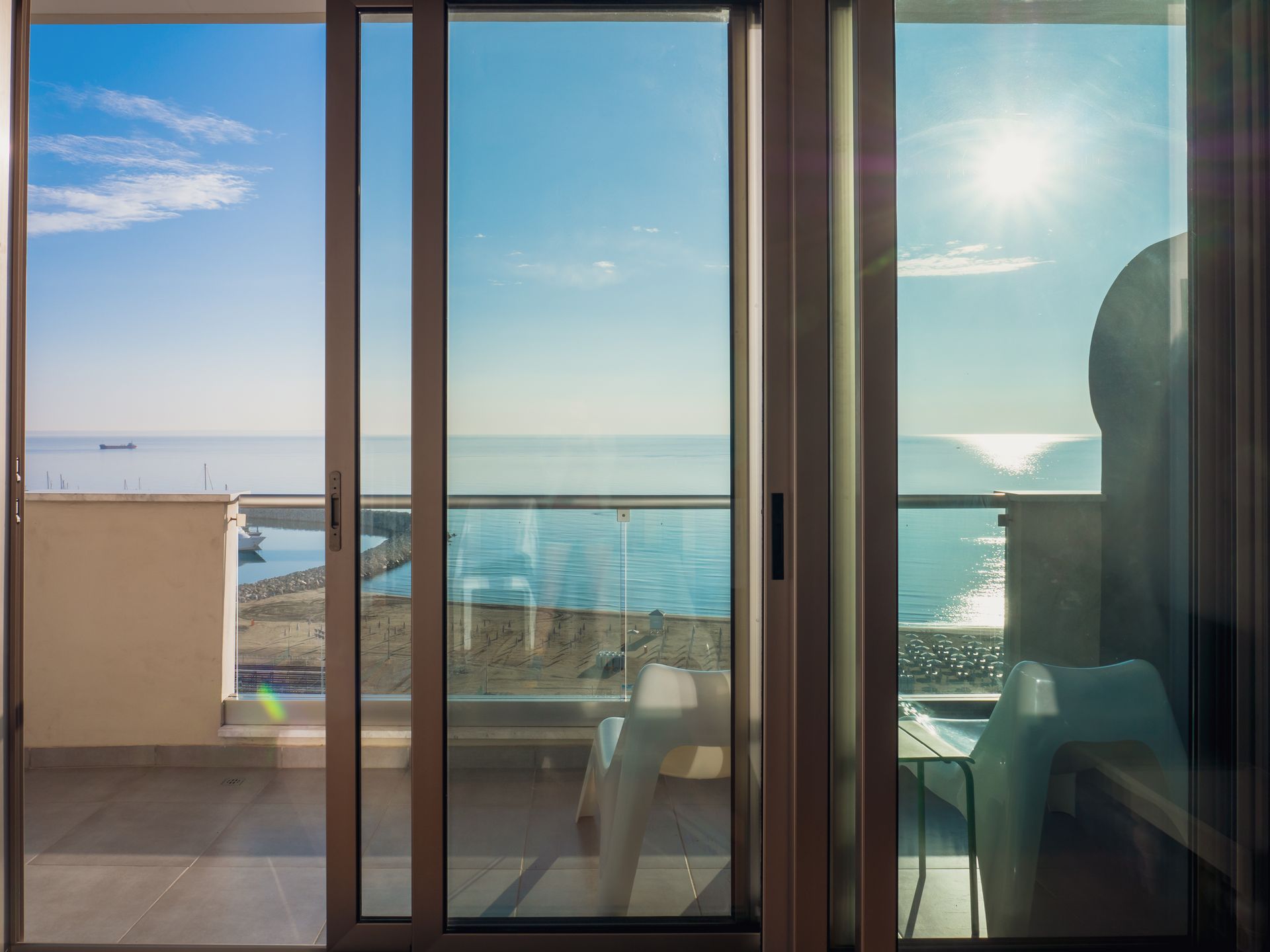 Photo d'une baie vitrée coulissante donnant sur un balcon avec vue sur la mer