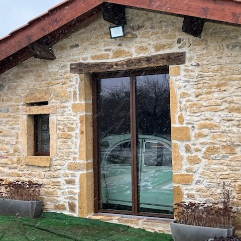 Maison en pierre dont la porte-fenêtre a été rénovée pour un modèle coulisant en aluminium