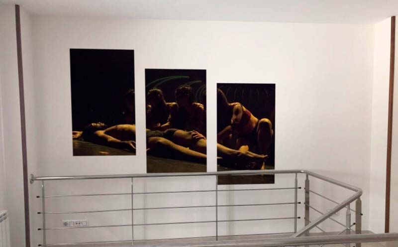 Tres obras de arte con motivos de caballos oscuros colgaban sobre el rellano de una escalera con barandilla de metal.