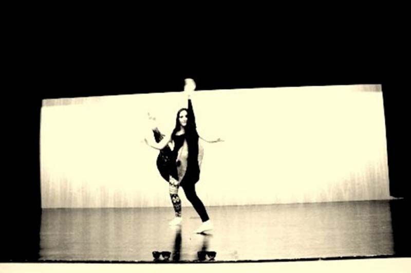 Fotografía en blanco y negro de una bailarina posando en un escenario con un brazo levantado.