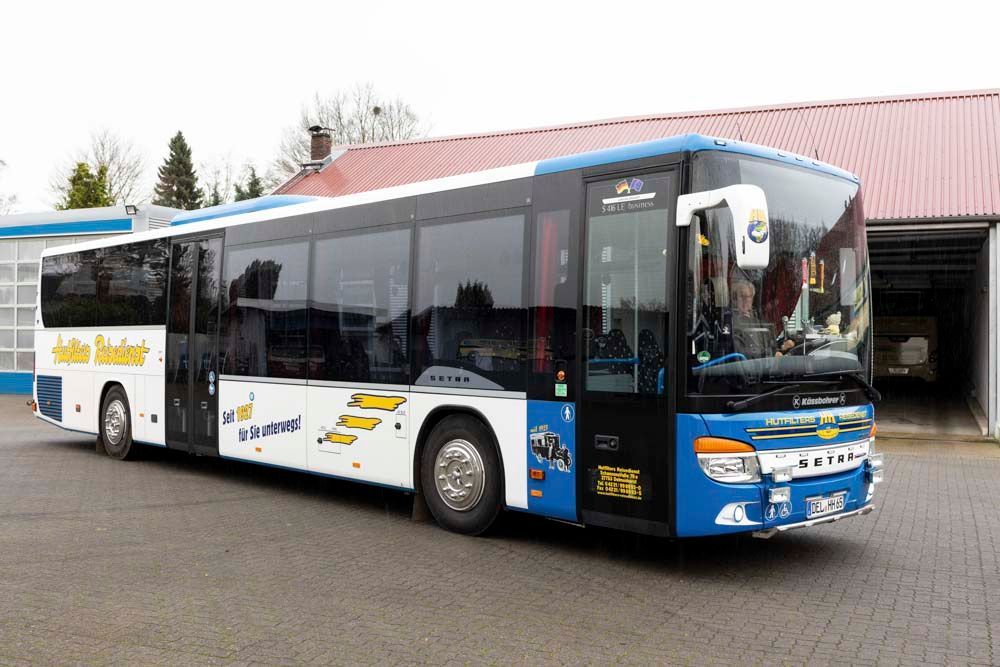 Ein blau-weißer Bus parkt vor einem Gebäude.