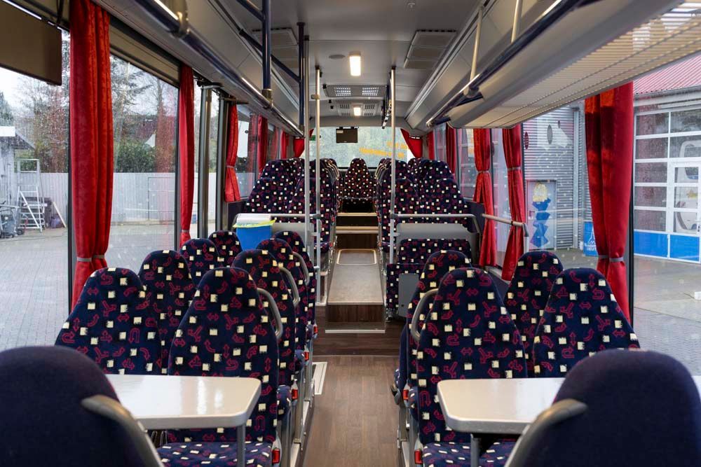 Das Innere eines Busses mit blauen Sitzen und roten Vorhängen