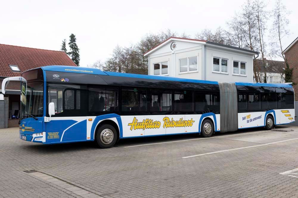 Ein blau-weißer Bus parkt vor einem Gebäude.