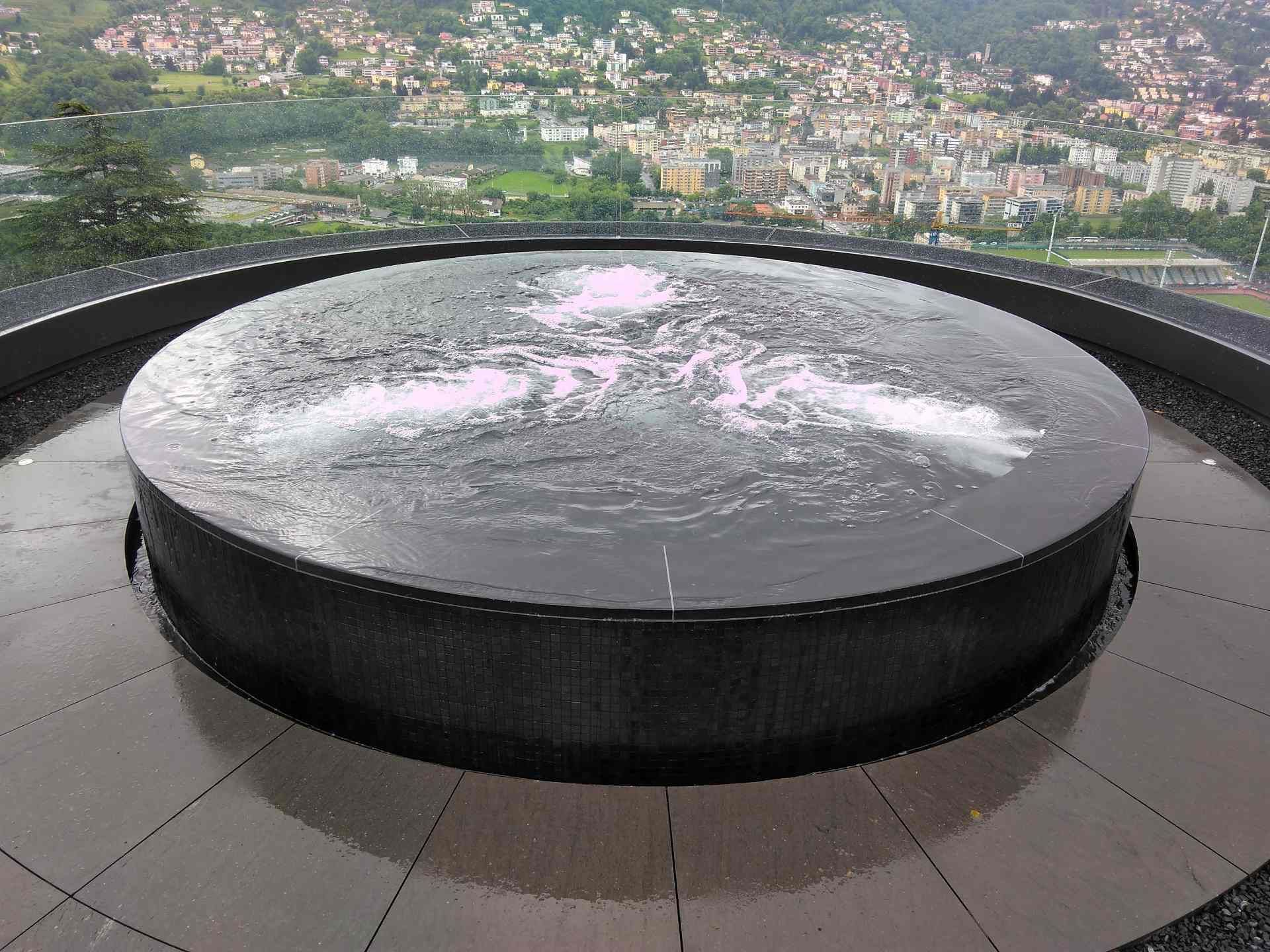 Ein runder Brunnen mit einer Stadt im Hintergrund