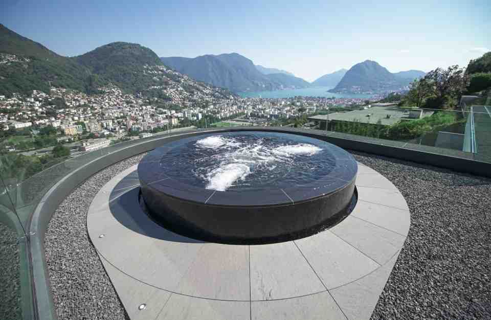 C'è una fontana sul tetto di un edificio con le montagne sullo sfondo.