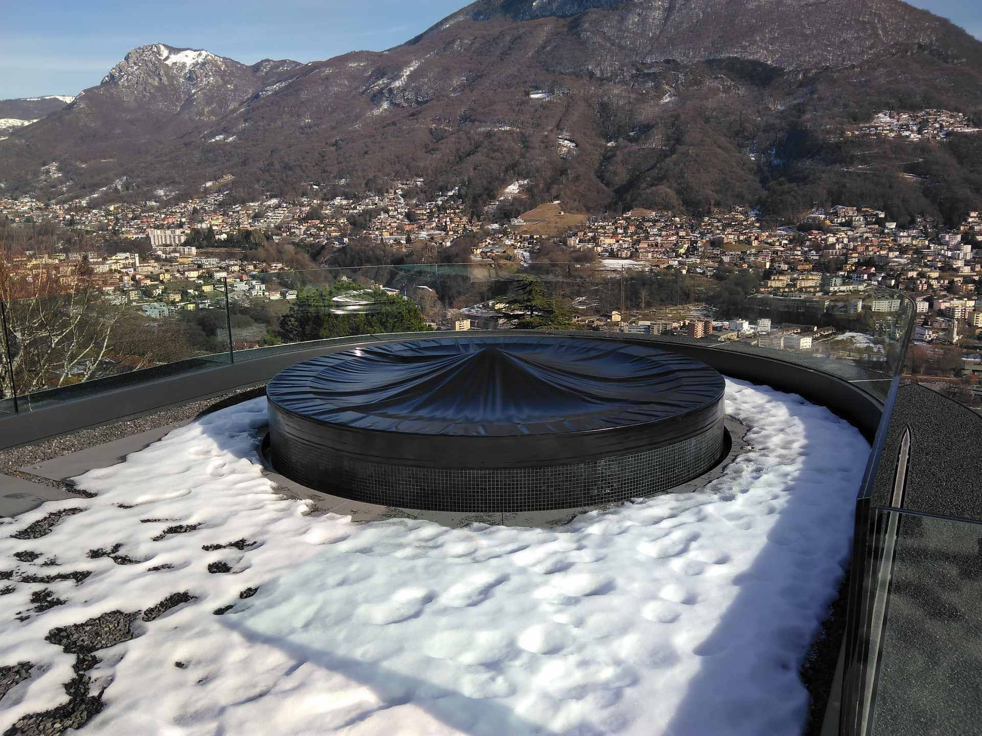 Un grande oggetto nero è circondato da neve e montagne sullo sfondo