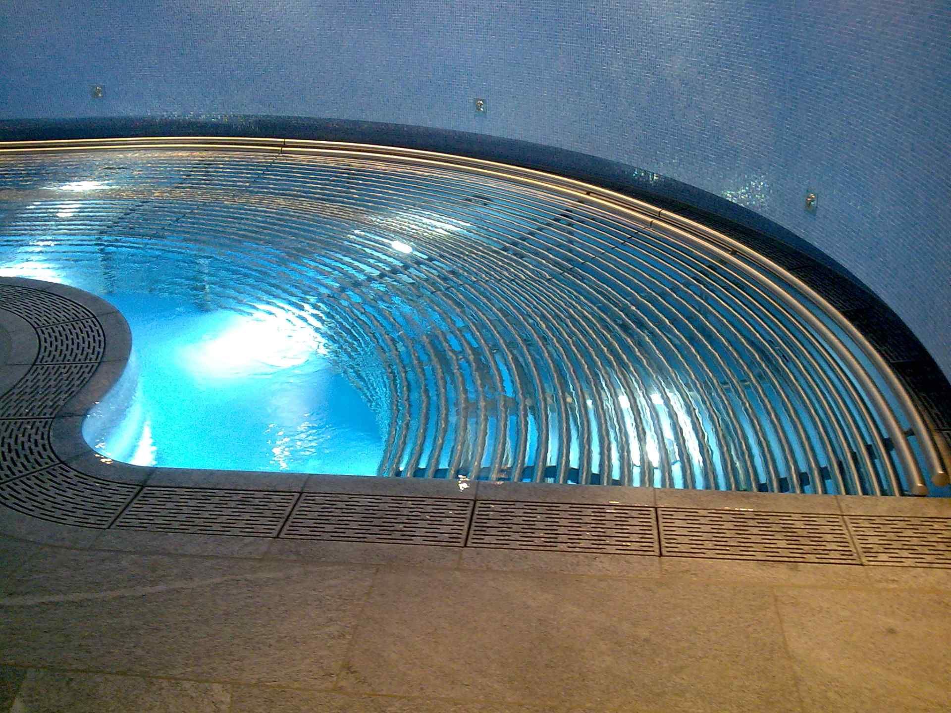 Una piscina con acqua blu e una ringhiera di metallo