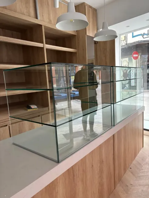 Vitrinas vacías en una tienda moderna con estantes de madera y lámparas colgantes.