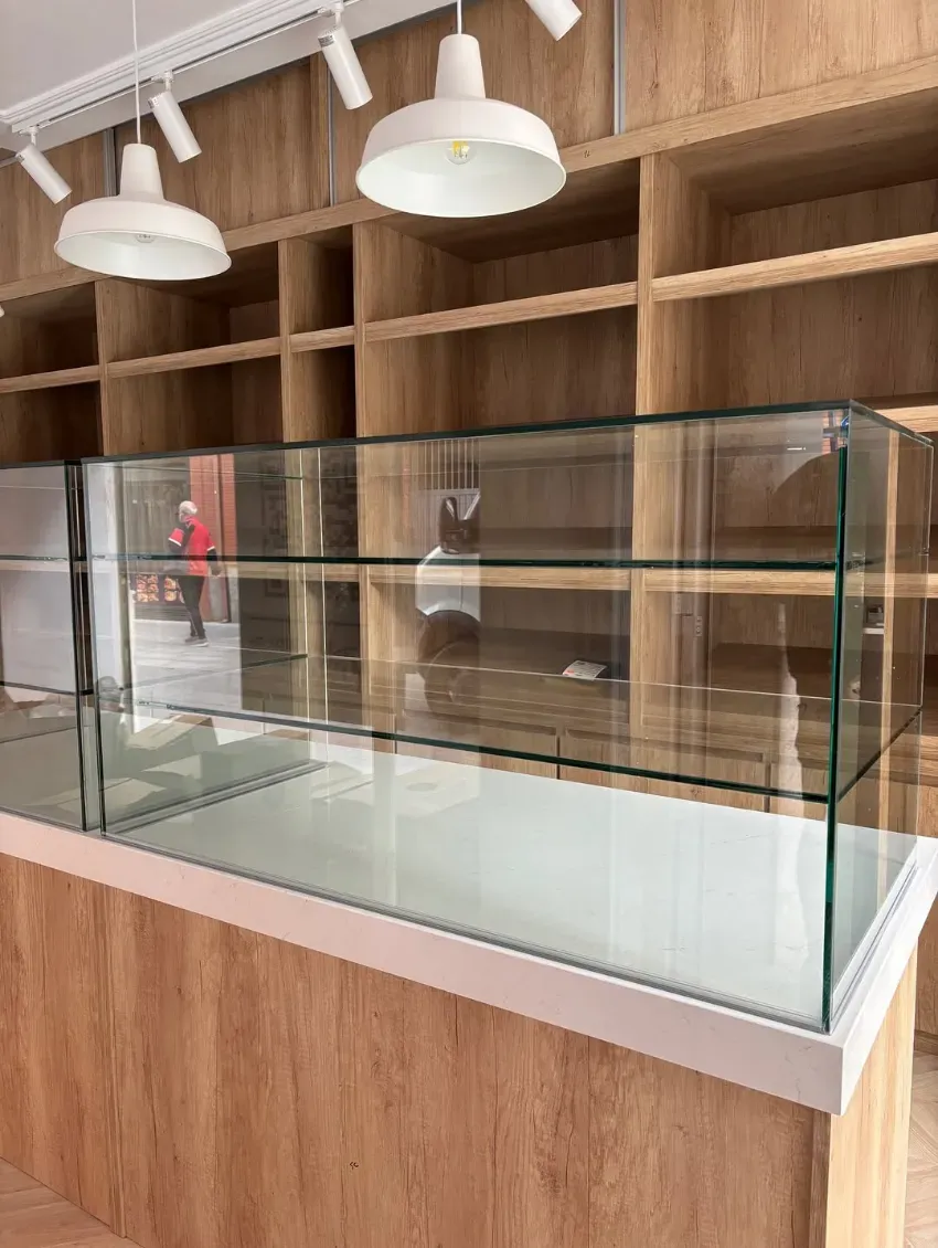 Vitrina vacía en una tienda moderna con estanterías de madera y focos empotrados en el techo.