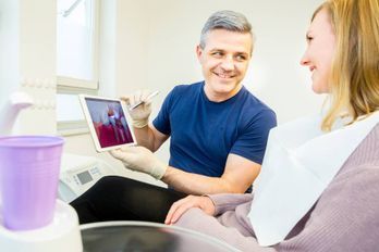 Zahnarzt Minor erklärt der Patienten etwas am Monitor
