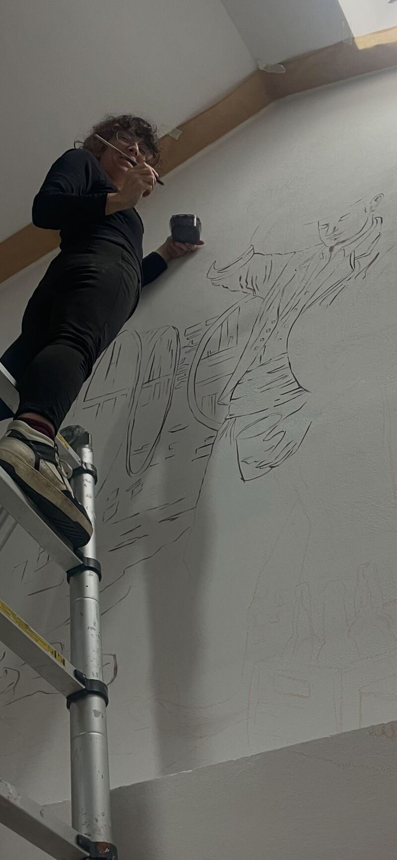 Una persona de pie en una escalera dibujando un gran boceto en una pared blanca
