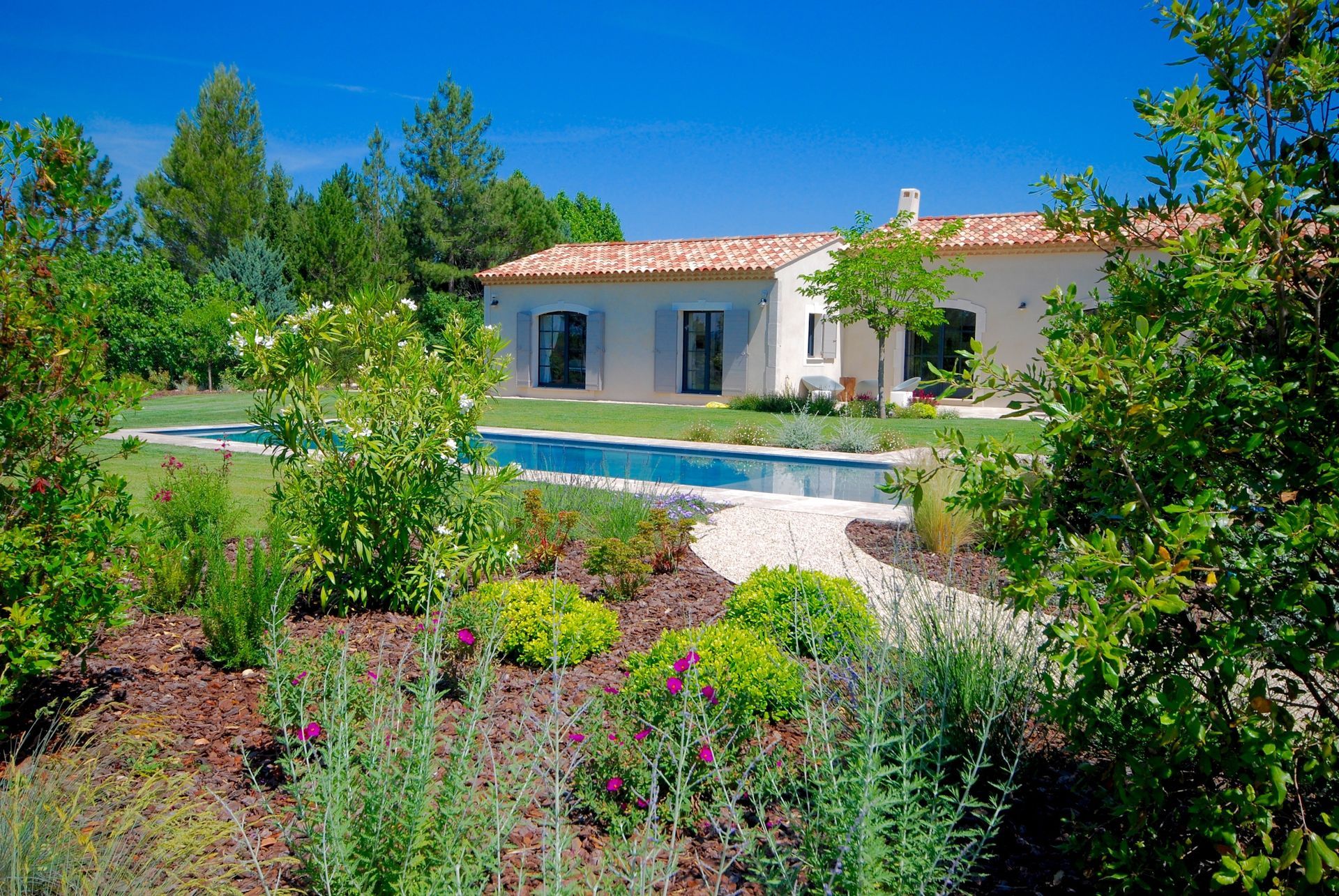 Jardin provençal devant une maison avec piscine