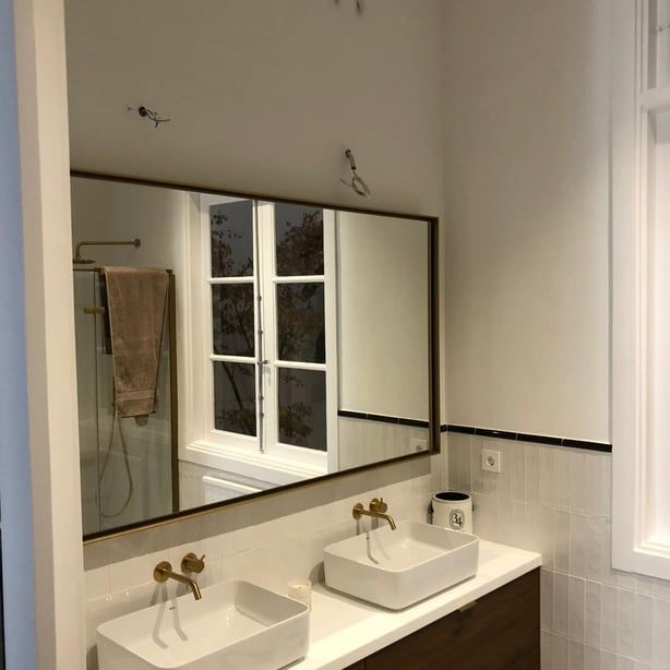 Un baño con dos lavabos y un espejo grande.