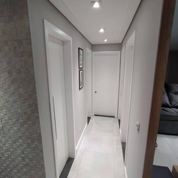 Un largo pasillo con un sofá y un sillón al fondo.