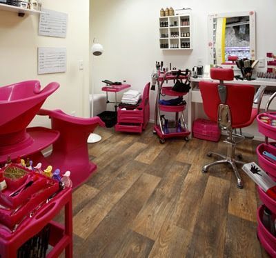 Una peluquería con sillas rosas y un lavabo.