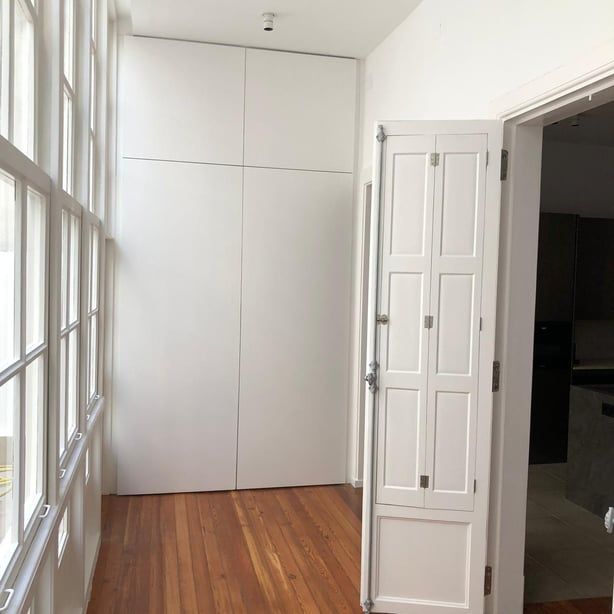 Un pasillo con pisos de madera y puertas blancas que conducen a una cocina.