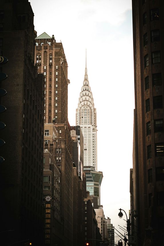 Edificio Chrysler, Nueva York, visto entre dos altos edificios marrones contra un cielo brillante.
