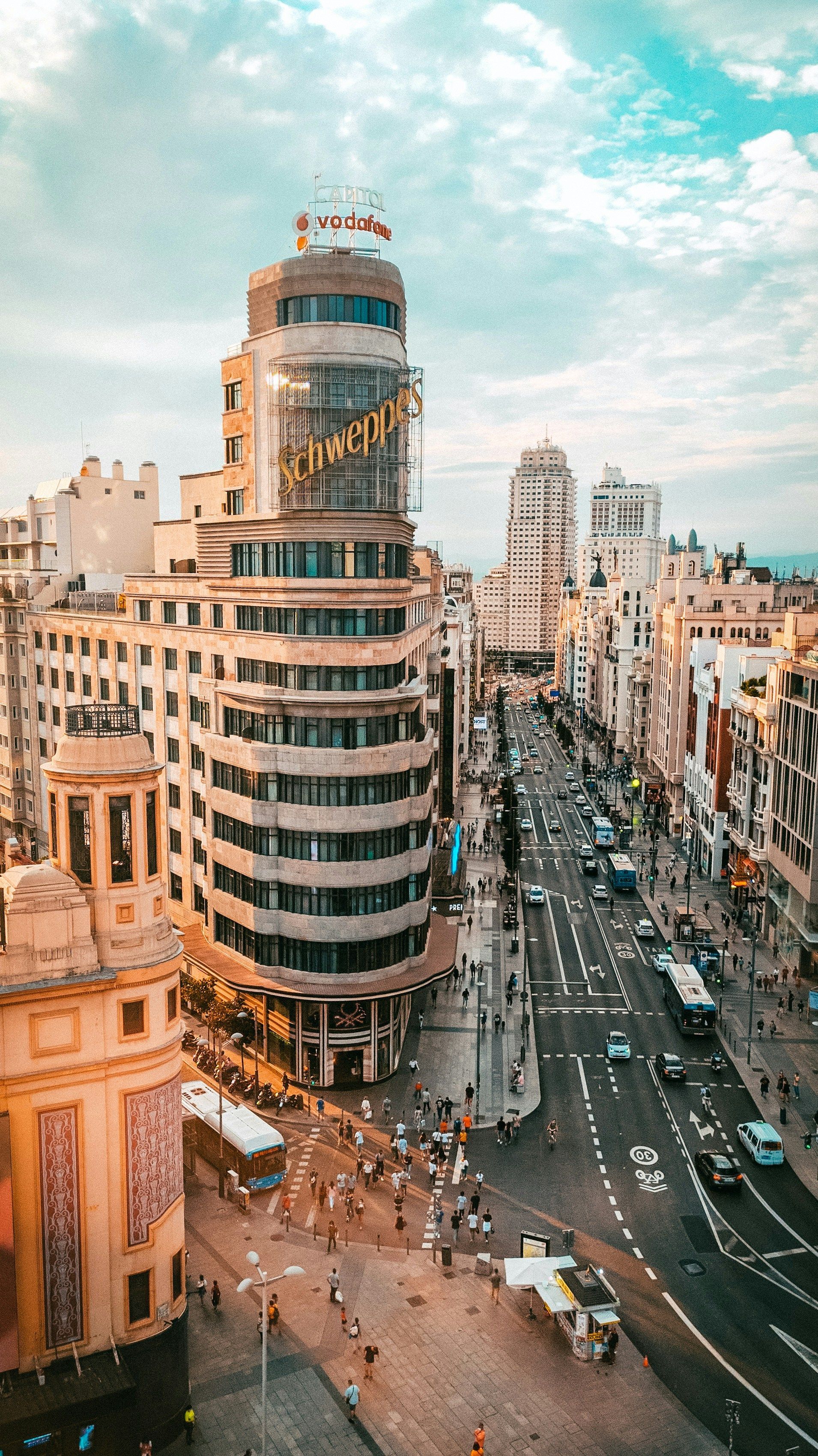 Vista del paisaje urbano de Madrid, donde se aprecia un edificio en forma de espiral y una calle muy transitada