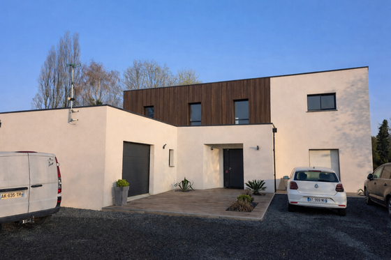 Maison en parpaings partiellement construite, avec toit en pente et cour ouverte, en construction