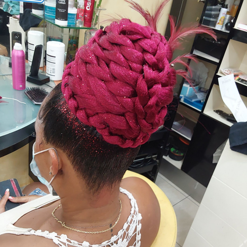 Cliente assise sur un fauteuil de salon avec une coiffure tressée rose vif
