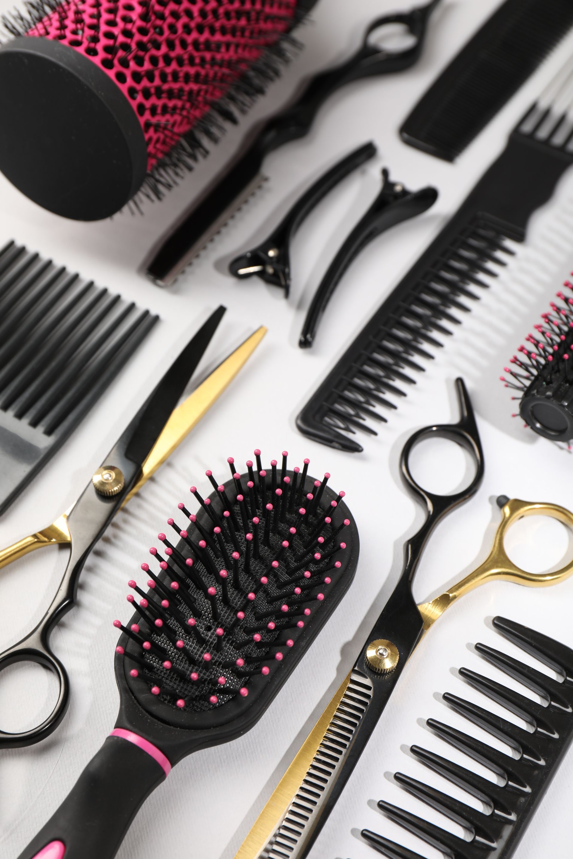 Assortiment de brosses à cheveux, peignes et ciseaux noirs et dorés sur fond blanc