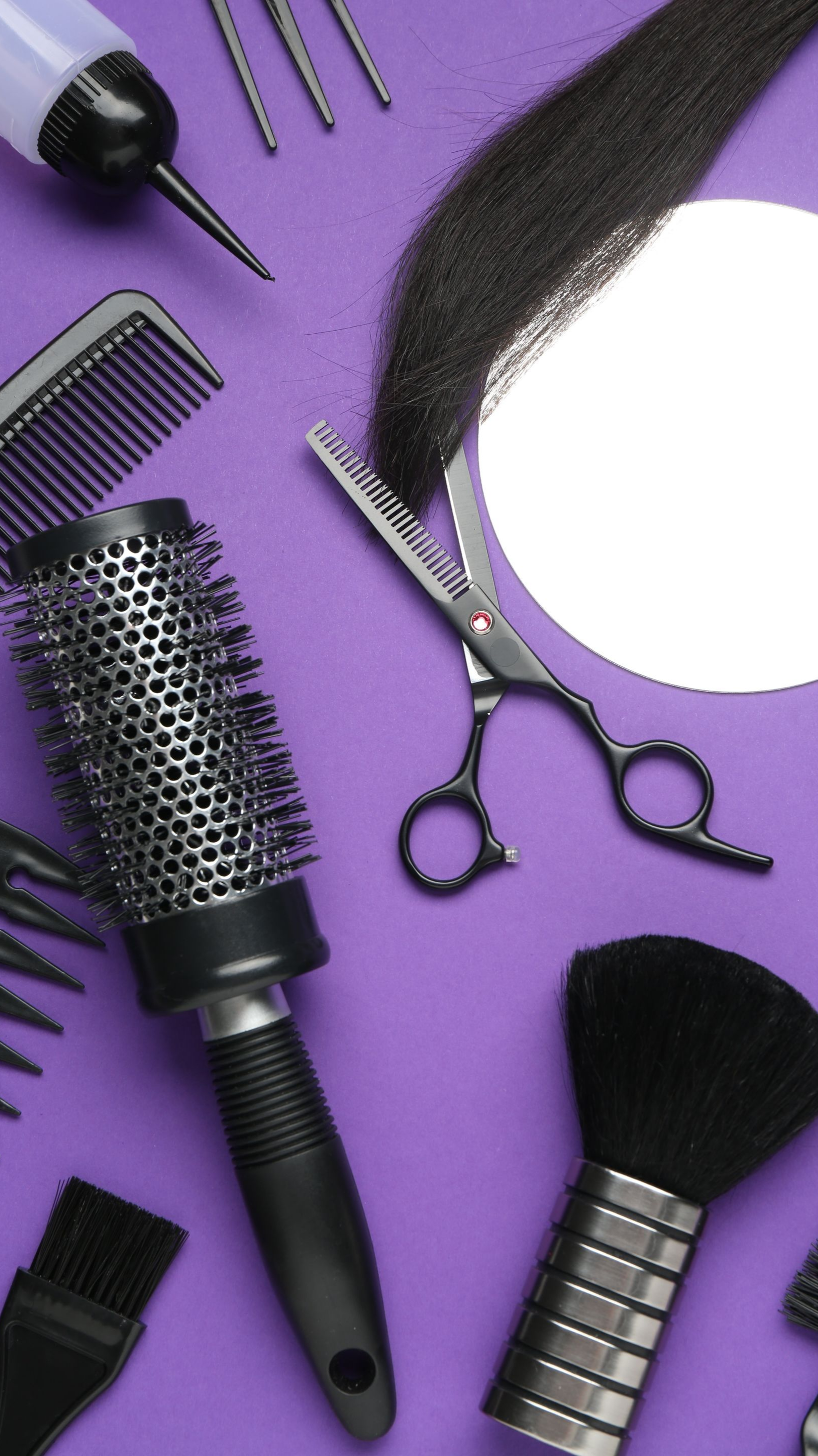 Outils de coiffure sur fond violet : brosse, peignes, ciseaux, brosse séchante et pinceau de maquillage.