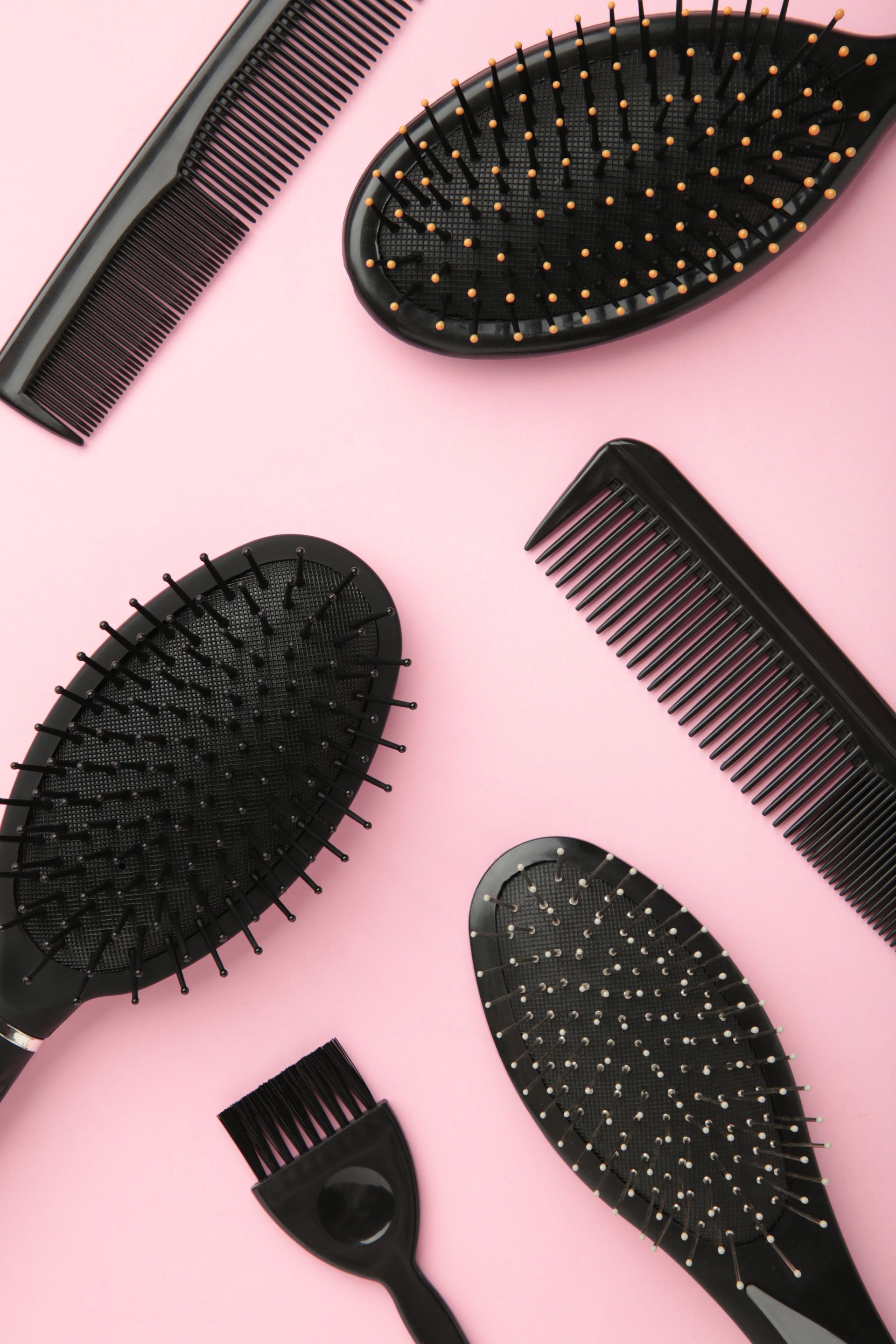 Assortiment de brosses à cheveux et de peignes noirs sur fond rose