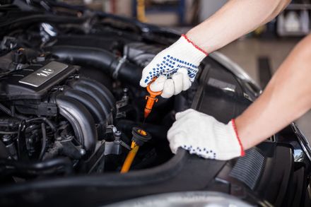 Un hombre está comprobando el aceite de un coche con una varilla de nivel.