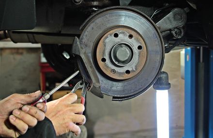 Un hombre está trabajando en un disco de freno de un coche en un garaje.