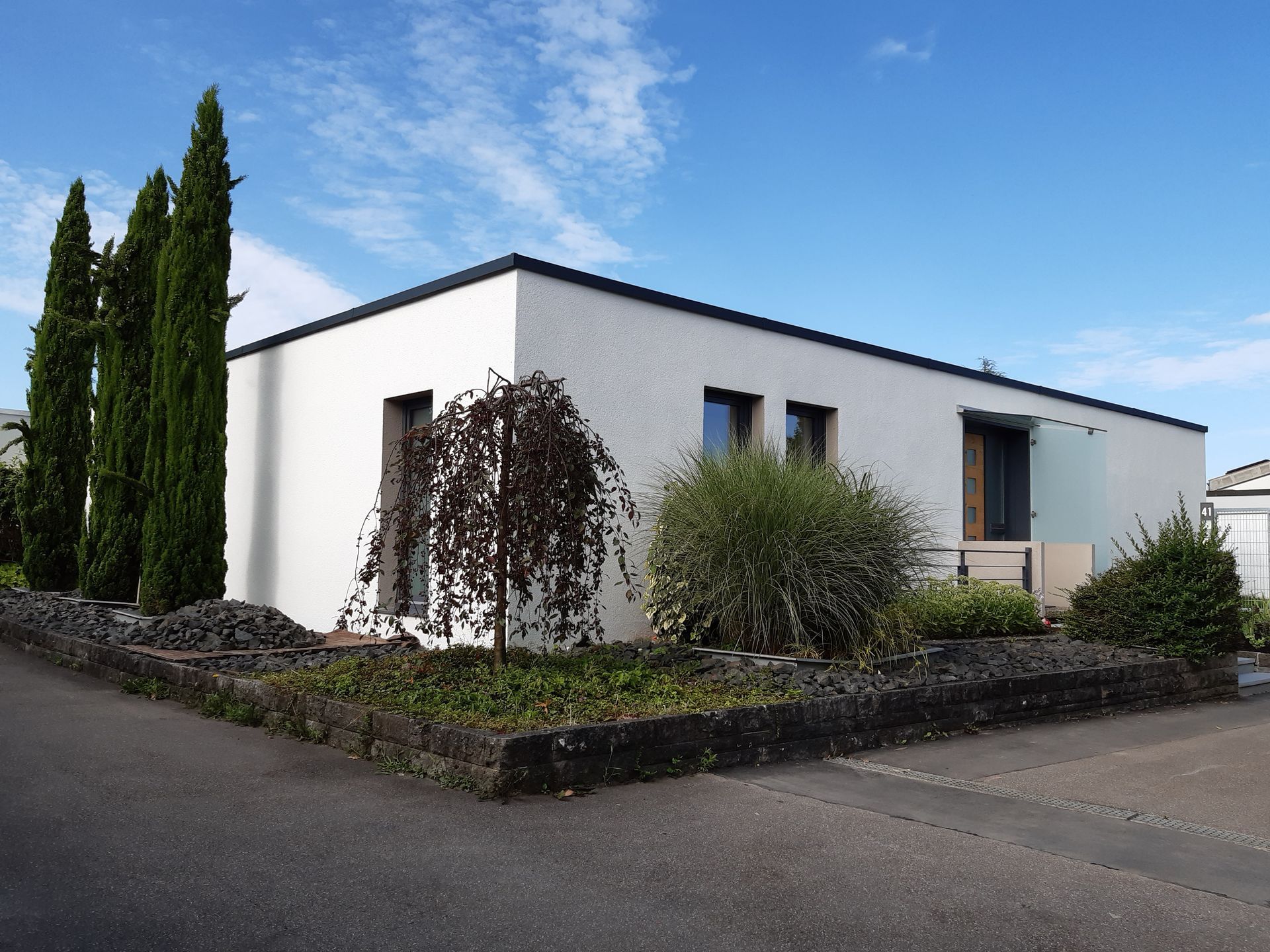 Ein weißes Haus mit Bäumen und Büschen davor