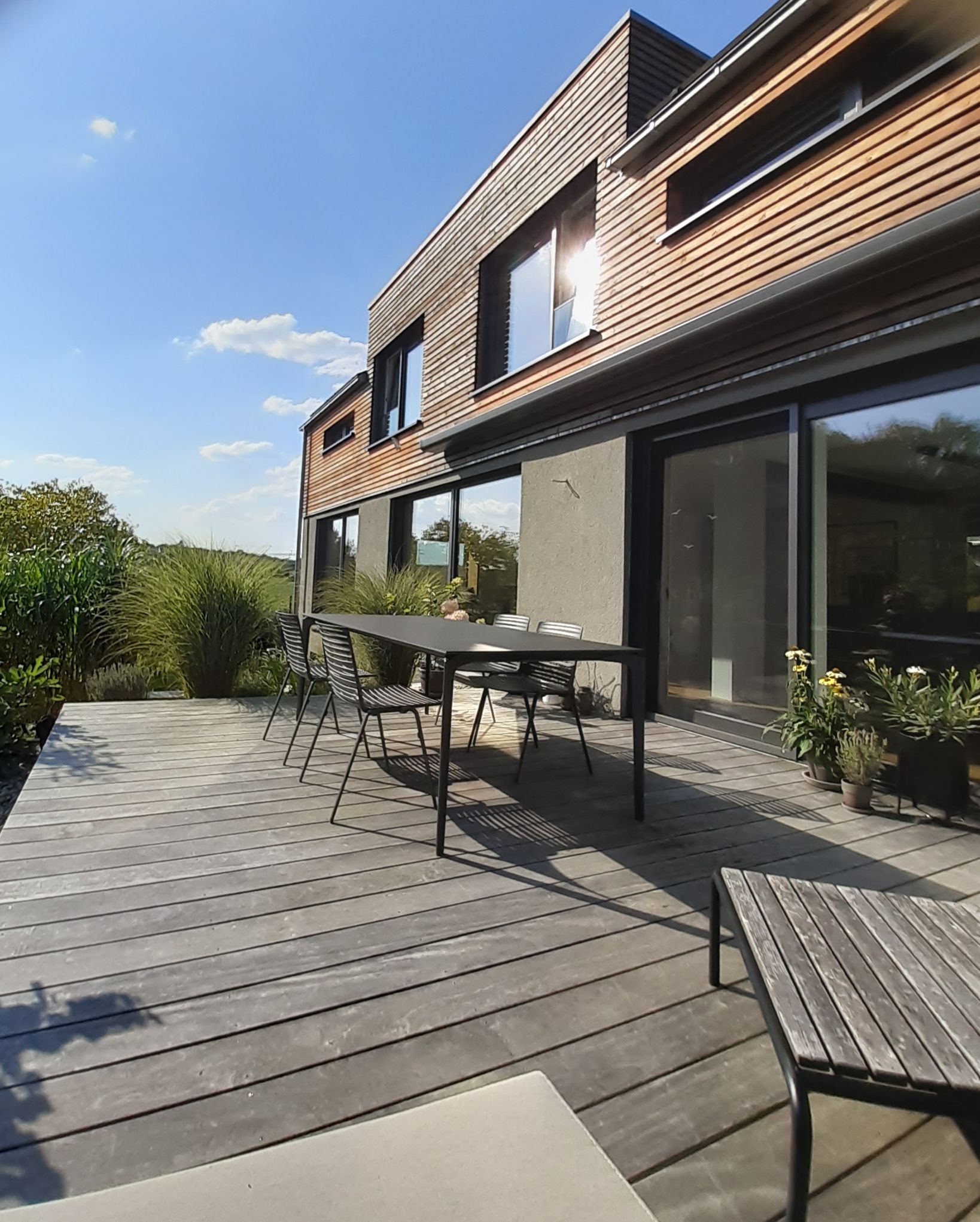 Eine Holzterrasse mit Tisch und Stühlen vor einem Haus.