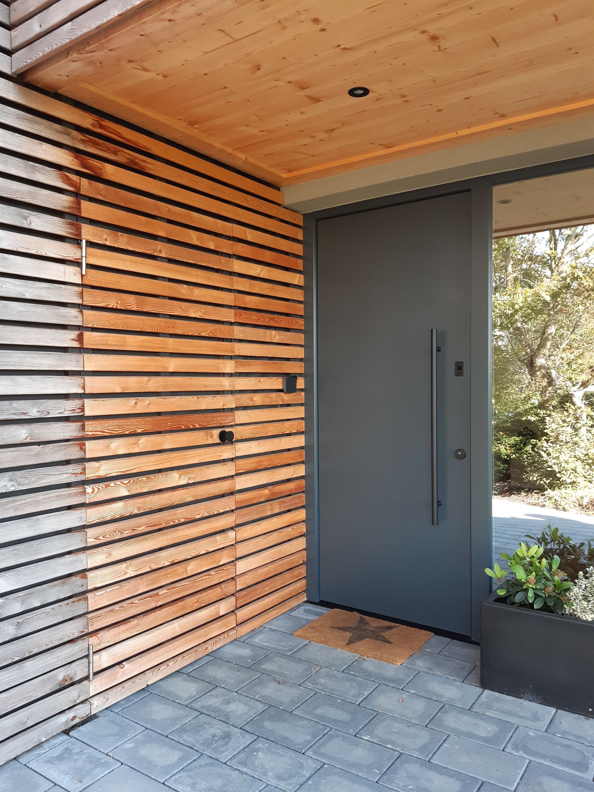 Eine schwarze Tür mit einer Holzwand dahinter