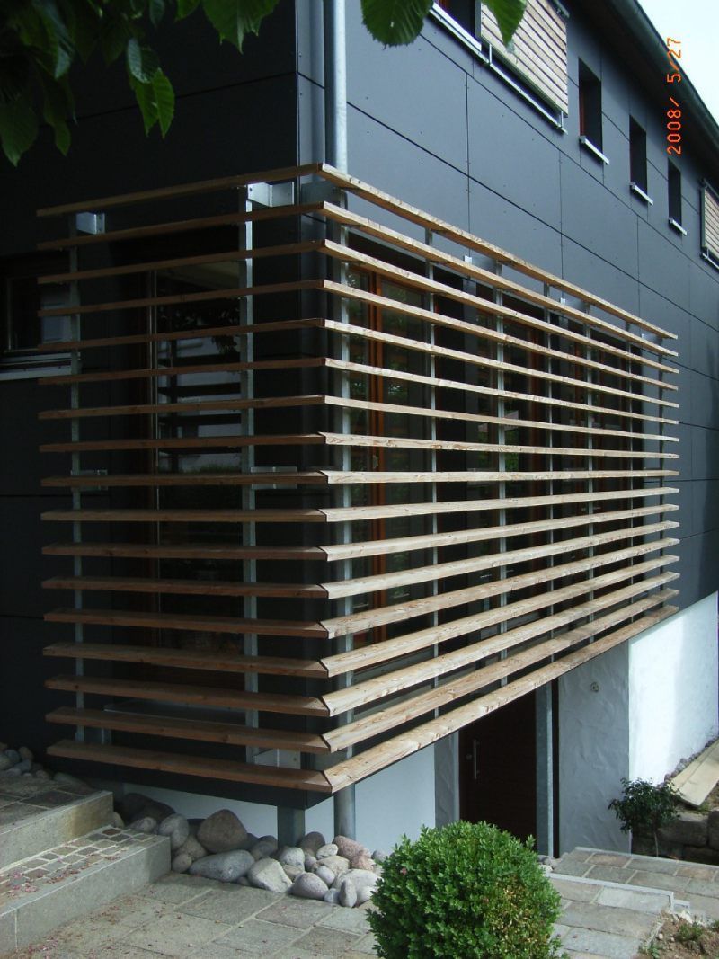 Ein schwarzes Gebäude mit einem Holzgeländer an der Seite