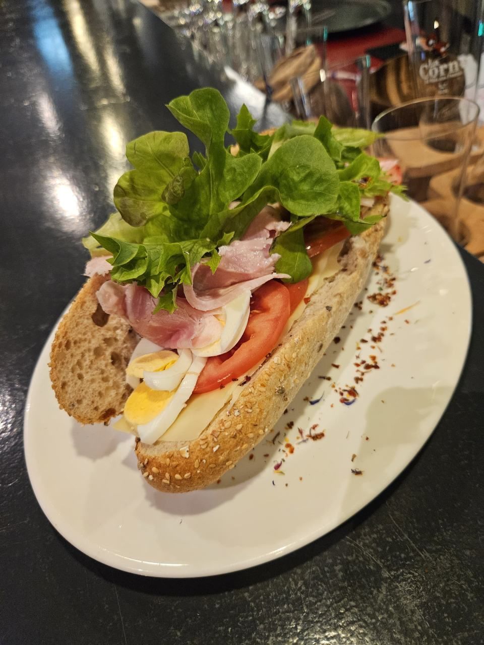 Une assiette blanche garnie d'un sandwich avec de la laitue, du jambon et des œufs