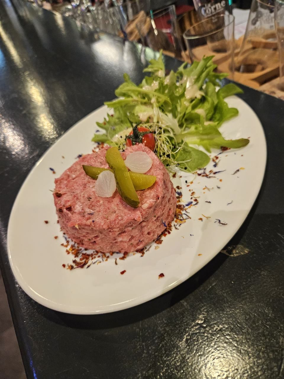 Une assiette blanche garnie de viande et de légumes sur une table.
