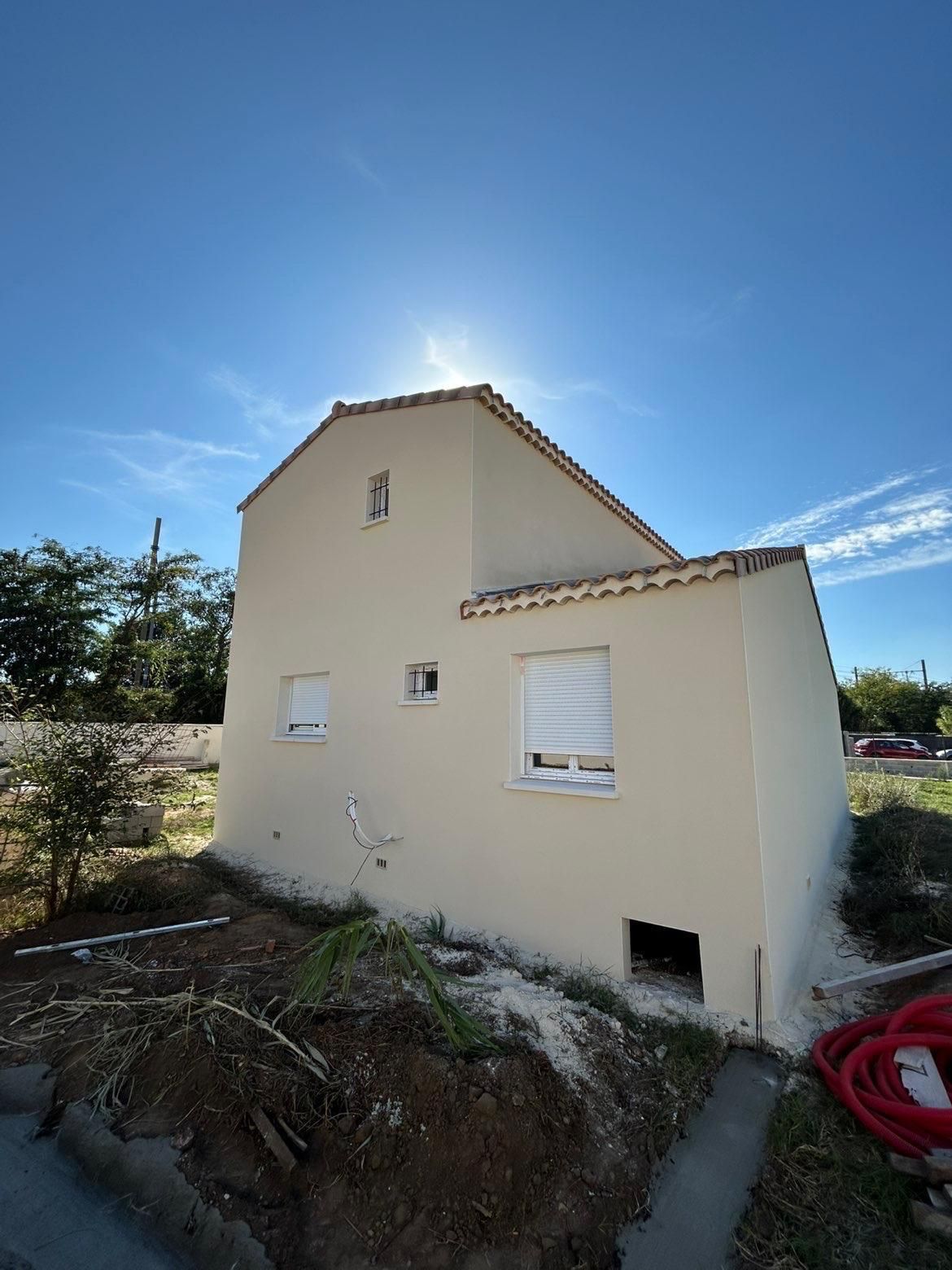 Maison beige en construction sur fond de ciel bleu éclatant.