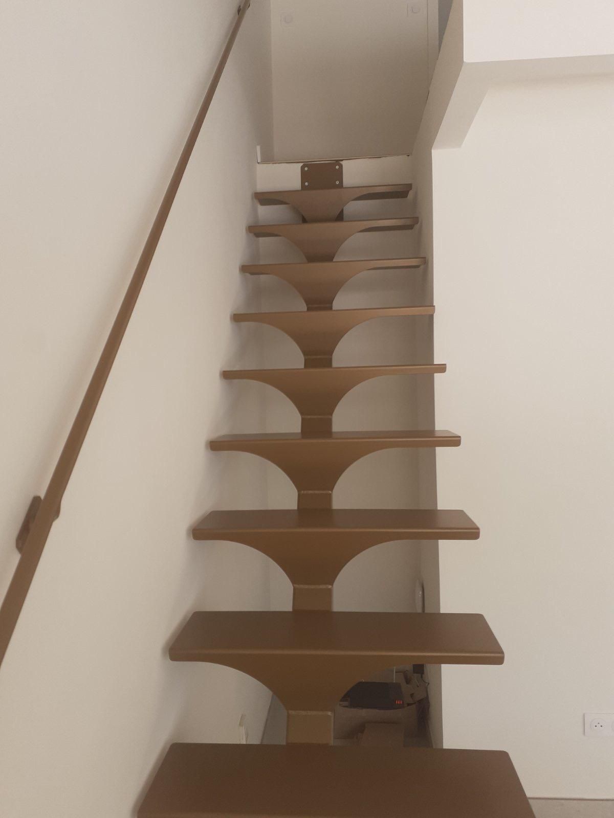 Escalier en bois brun contre un mur blanc avec une rampe brune.