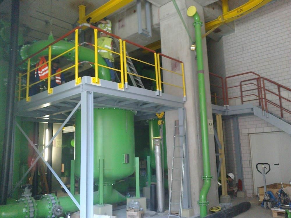 Ein Mann steht auf einer Plattform in einem Raum mit grünen Rohren