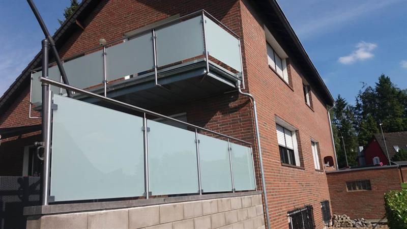 Ein Backsteingebäude mit Balkon und Glasgeländer