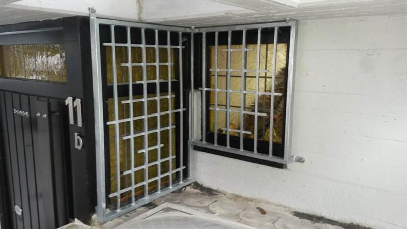 Ein Gebäude mit einer schwarzen Tür und einem vergitterten Fenster.