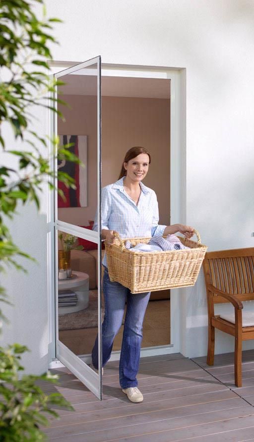 Eine Frau trägt einen Wäschekorb durch eine Fliegengittertür.
