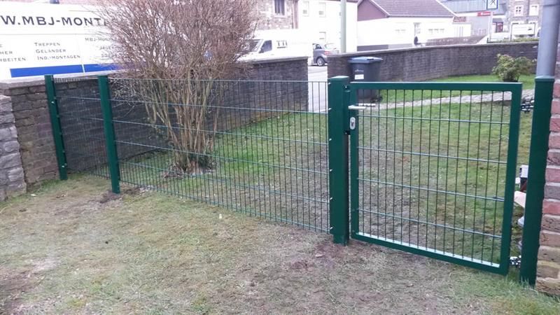 Ein grüner Zaun mit einem offenen Tor