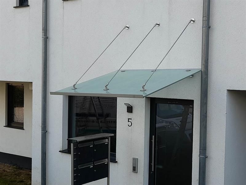 Ein weißes Gebäude mit einem Glasdach über der Tür