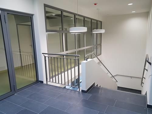 Eine Treppe in einem Gebäude mit einem Geländer und vielen Fenstern.