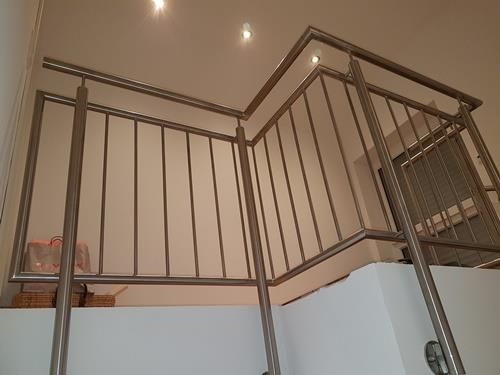 Eine Treppe mit Edelstahlgeländer und weißer Wand.