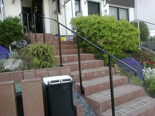 Eine Treppe, die zu einem Haus mit einem schwarzen Geländer führt