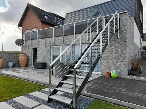 Eine Treppe, die zu einem Balkon vor einem Haus führt.