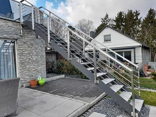 Eine Treppe, die zu einem Haus mit einem Edelstahlgeländer hinaufführt.